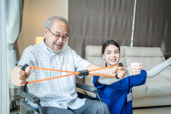 Senior man in a wheelchair doing resistance band exercises with an occupational therapist to improve mobility and independence.