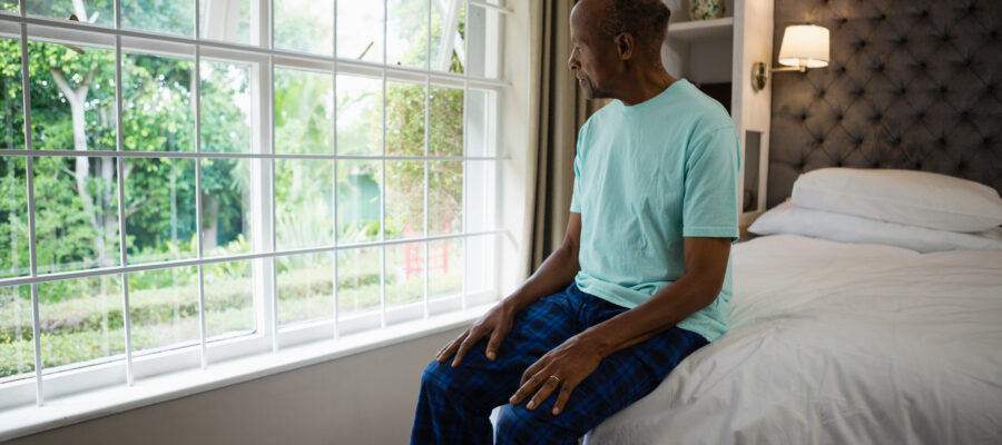thoughtful-senior-man-sitting-on-bed-by-window-in-2025-10-28-21-52-02-utc