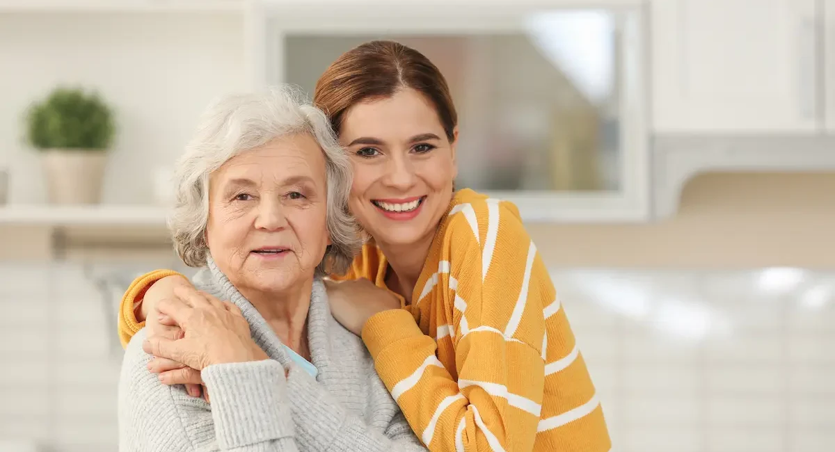 smiling-woman-hugging-senior-woman-in-kitchen-2026-03-05-11-32-22-utc-caringfamily